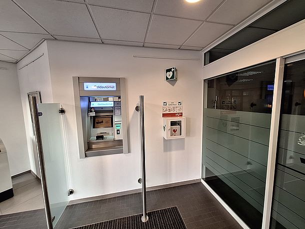 AED im Wandkasten rechts neben dem Geldautomaten