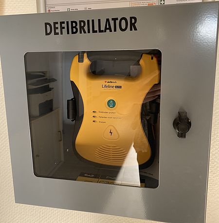 gelber AED im Wandkasten