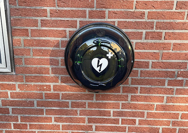 AED Gerät im beleuchteten und alarmgesicherten Außenkasten an der Hauswand